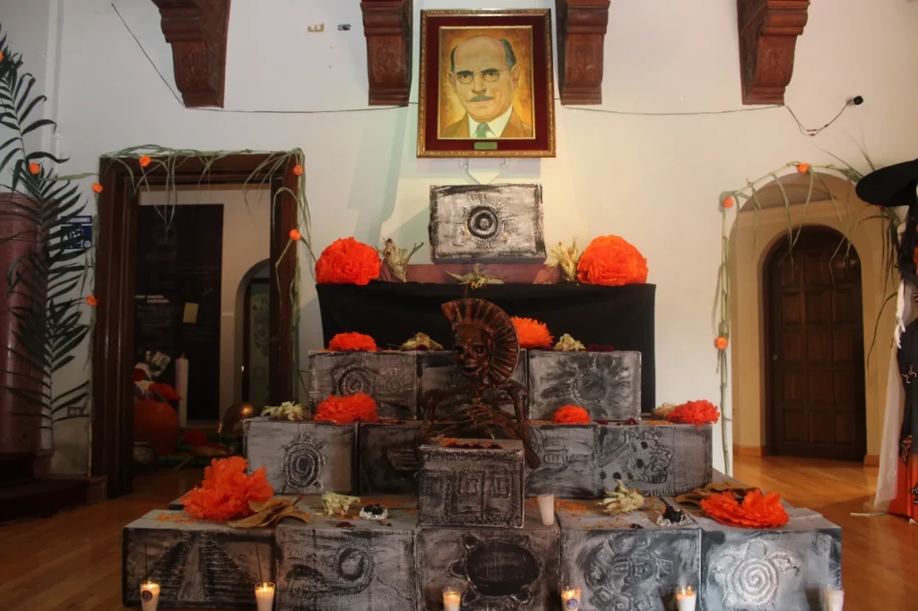 Altar escalonado de Día de Muertos con calavera, flores de cempasúchil y un retrato enmarcado