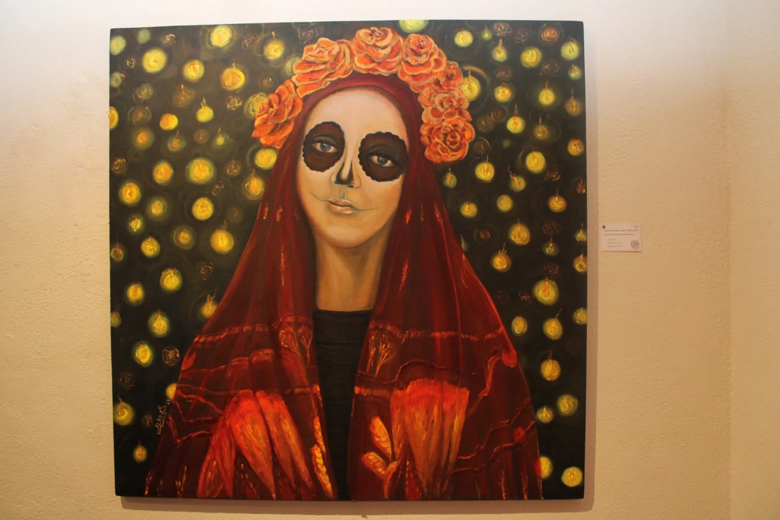 Pintura de una catrina con velo rojo y corona de flores, acompañada de velas