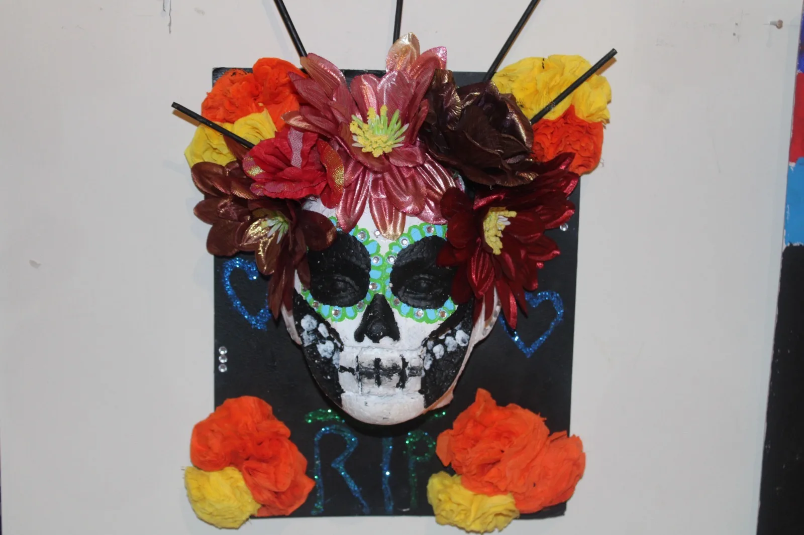 Máscara de calavera decorada con flores de colores y la palabra RIP