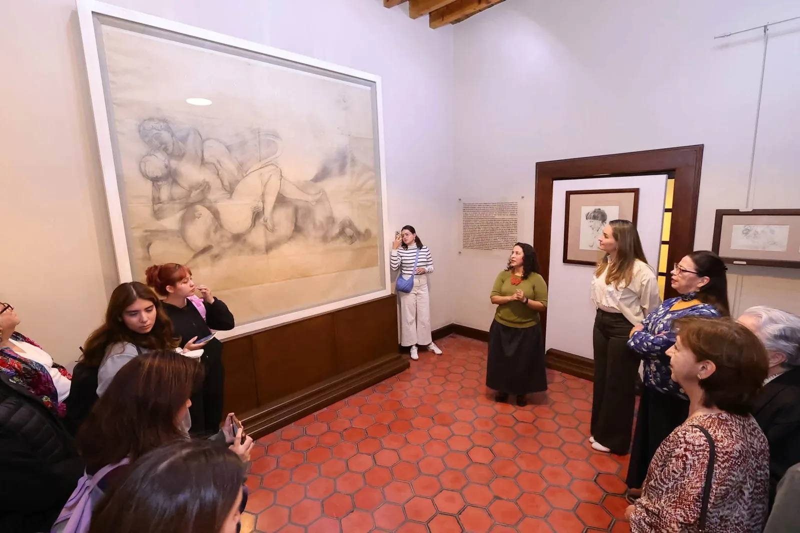 Visitantes frente a un dibujo de gran formato en la exposición Concluir al centauro